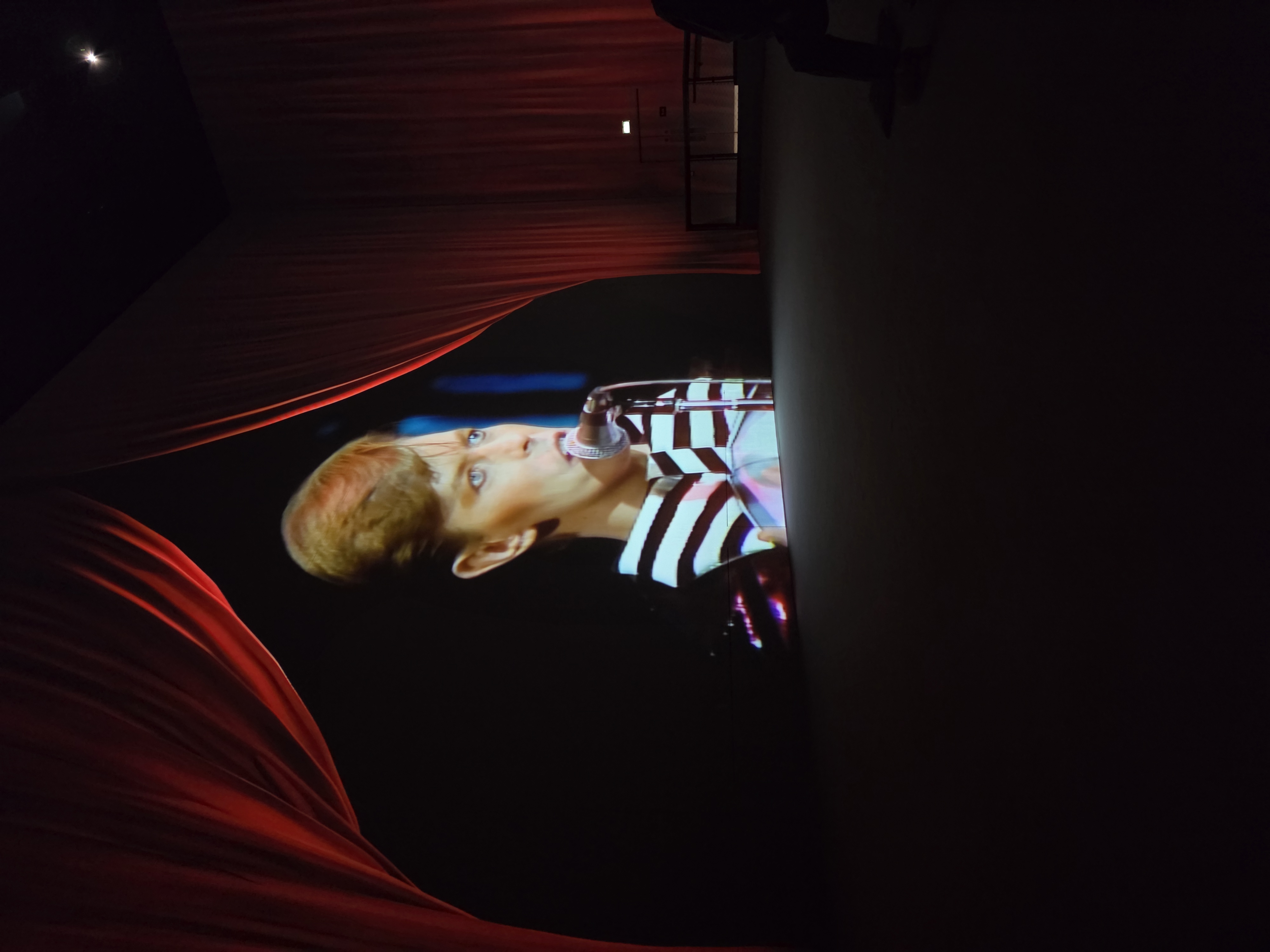 Red curtains framing Bowie on stage